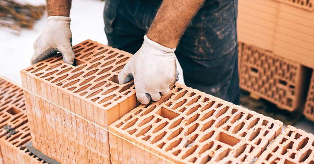 Ein Maurer beim Setzen von Ziegelsteinen