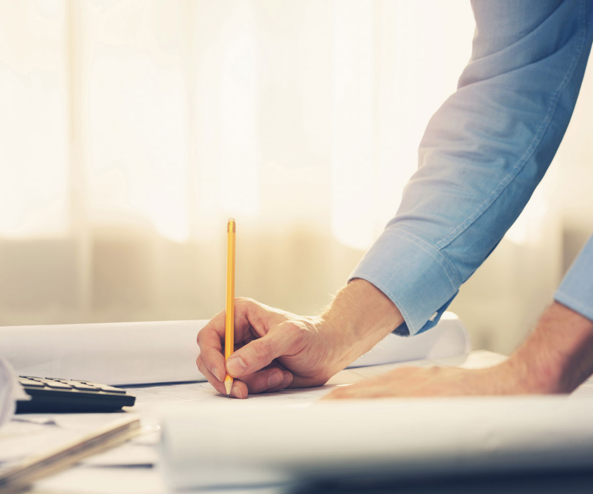 Zeichner mit Bauplan auf Schreibtisch